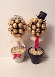 two vases filled with gold and white chocolate covered balls, each decorated with a red ribbon