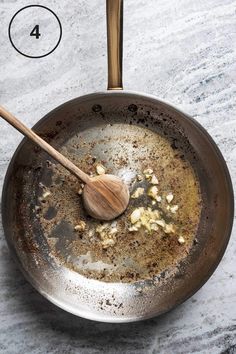 a frying pan filled with some food and a wooden spoon on top of it