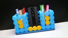 a cell phone holder made out of plastic bottles and pencils on top of a table