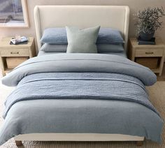 a bed with blue linens and pillows in a small room next to two nightstands