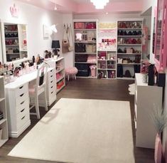 a room filled with lots of white furniture and pink accents on the walls, along with shelves full of personal items