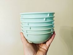 a hand holding a stack of blue bowls