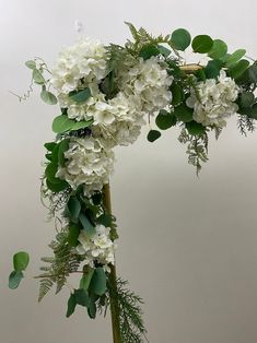 white flowers and greenery are arranged on a pole