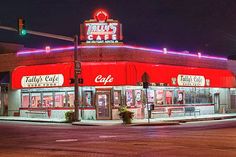 an empty street at night in front of a restaurant with red awnings and neon lights