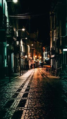 an empty city street at night with no one on the sidewalks or people walking down it