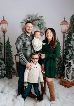 a family poses in front of christmas trees