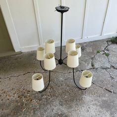 a set of five candles on a stand outside with the door open and white walls behind it