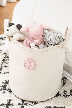 a stuffed animal in a personalized storage bin on a rug with a monogrammed pillow