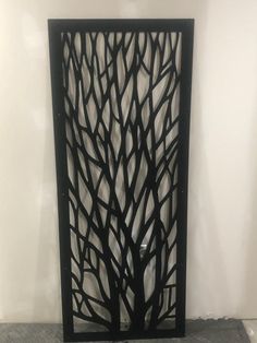 an iron screen with trees on it in the corner of a room, against a white wall