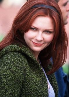 a woman with red hair is smiling at the camera