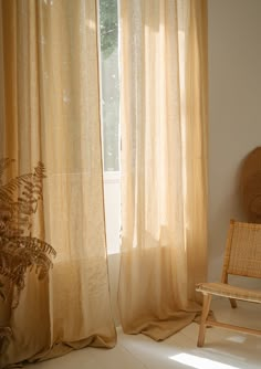 a chair sitting in front of a window next to a wooden bench and curtained windows