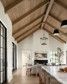 a large open concept kitchen and dining room with wood ceilinging, white walls and wooden beams