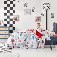 a little boy sitting on top of a bed in a room with checkered walls