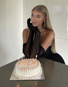 a woman sitting in front of a cake with candles on it