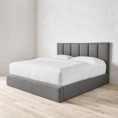 a bed that is sitting on top of a hard wood floor in a white room