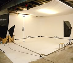 an empty photo studio with white walls and lighting equipment in front of the camera set up