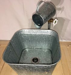 a metal bucket with a water faucet on top of it