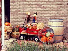 a wagon filled with pumpkins and hay sitting in front of a brick building next to a barrel