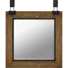 a wooden frame mirror hanging on the wall with two black metal hooks attached to it