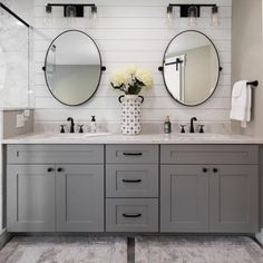 a bathroom with two sinks, mirrors and flowers in vases on the counter top