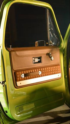 an old green car with the door open and it's interior showing wood trim