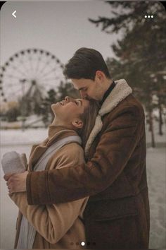 a man and woman kissing in front of a ferris wheel