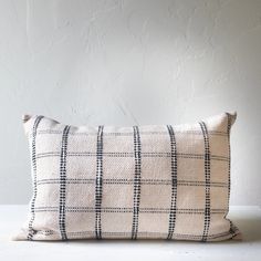 a black and white checkered pillow sitting on top of a wooden table next to a wall