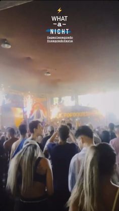 a large group of people standing in a room with lights on the ceiling and one person holding his head up