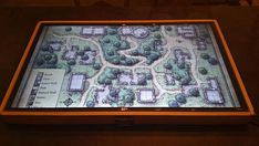 a large display with a map on it in front of a table top that is lit up