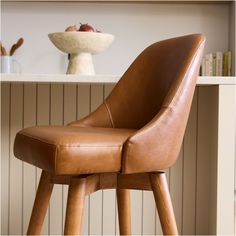 a brown leather chair sitting in front of a shelf with fruit on top of it