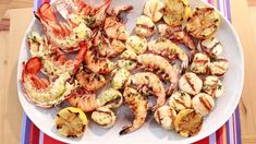 a white plate topped with grilled shrimp and lemon wedges