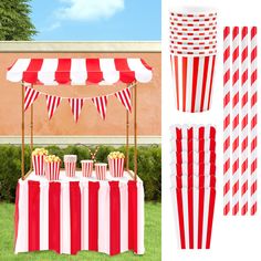 red and white striped paper cups with popcorn on the table in front of a tent