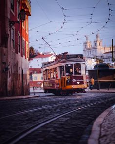 an orange trolley car traveling down a street next to tall buildings