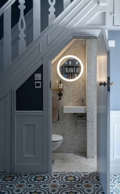 an open door leading to a bathroom with a toilet and sink under a stair case