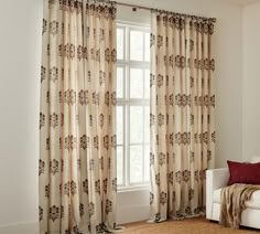 a living room with a white couch and two curtains on the window sill, in front of a large window