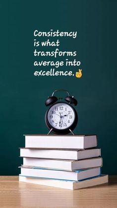 a stack of books with an alarm clock on top and a chalkboard in the background