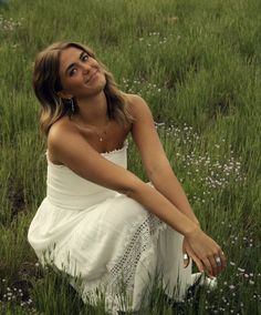 a beautiful young woman sitting in the grass