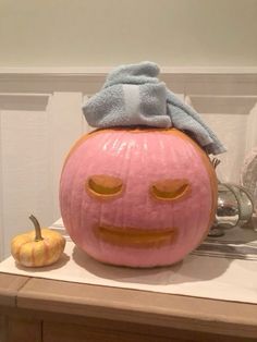 a large pumpkin with a towel on top of it's head sitting on a counter