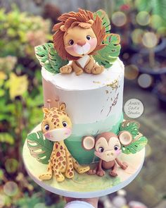 a hand holding a cake decorated with an animal and giraffe on the top