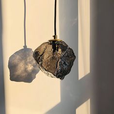 a glass object hanging from a wire next to a window with the light shining on it