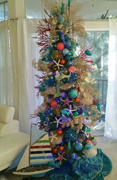 a christmas tree decorated with colorful ornaments and seashells is shown in this living room