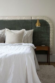 a bed with white linens and pillows in a small room next to a lamp