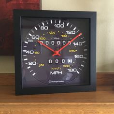 a black clock with red hands on a wooden table