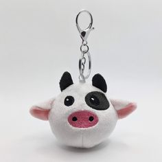 a white and black stuffed animal keychain with a pink nose on it's side