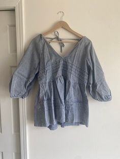 This soft denim shirt is cute! It has a tie at the top of the back and a deep V in both the front and back.  Size large Chic Spring Denim V-neck Top, Chic V-neck Denim Top For Spring, Summer V-neck Washed Tops, Washed Denim Top For Day Out, Relaxed Fit Light Wash Denim Top For Day Out, Relaxed Fit Denim Top For Spring Day Out, Washed Chambray Denim Top For Day Out, Chic Light Wash Chambray Denim Top, Chic Light Wash Relaxed Fit Denim Top