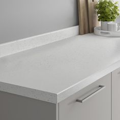 a white counter top in a kitchen with a potted plant on the countertop