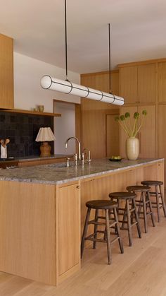 a kitchen with wooden cabinets and stools next to an island counter top that has four bar stools in front of it