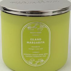 a candle that is sitting on a white counter top with a silver lid and the words island margarita in front of it