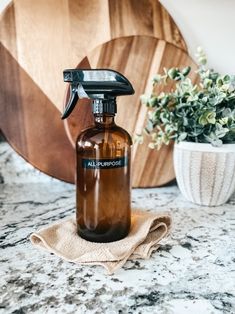 a brown glass spray bottle sitting on top of a counter next to a potted plant