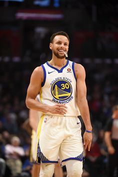 a man standing on top of a basketball court wearing a white and blue uniform with the golden state warriors written on it